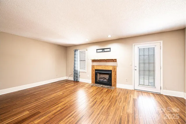 a view of empty room with wooden floor and fireplace