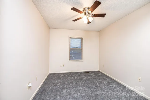 an empty room with a window and a ceiling fan