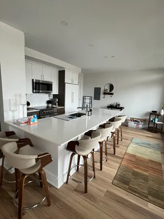 a living room with stainless steel appliances kitchen island granite countertop furniture wooden floor and a view of kitchen