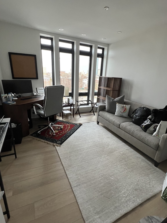 1950 Washington Street, Unit 5C Boston, MA 02118 - Photo 5 of 11 a living room with furniture a flat screen tv and a floor to ceiling window