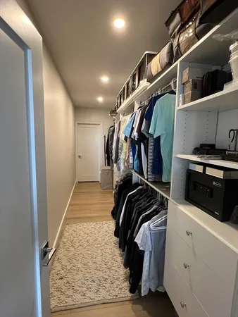 a view of walk in closet with clothes and shoes