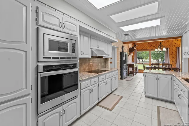 a kitchen with stainless steel appliances granite countertop a stove and white cabinets