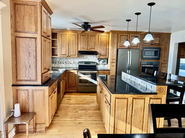 a kitchen with stainless steel appliances granite countertop a refrigerator a stove and a sink