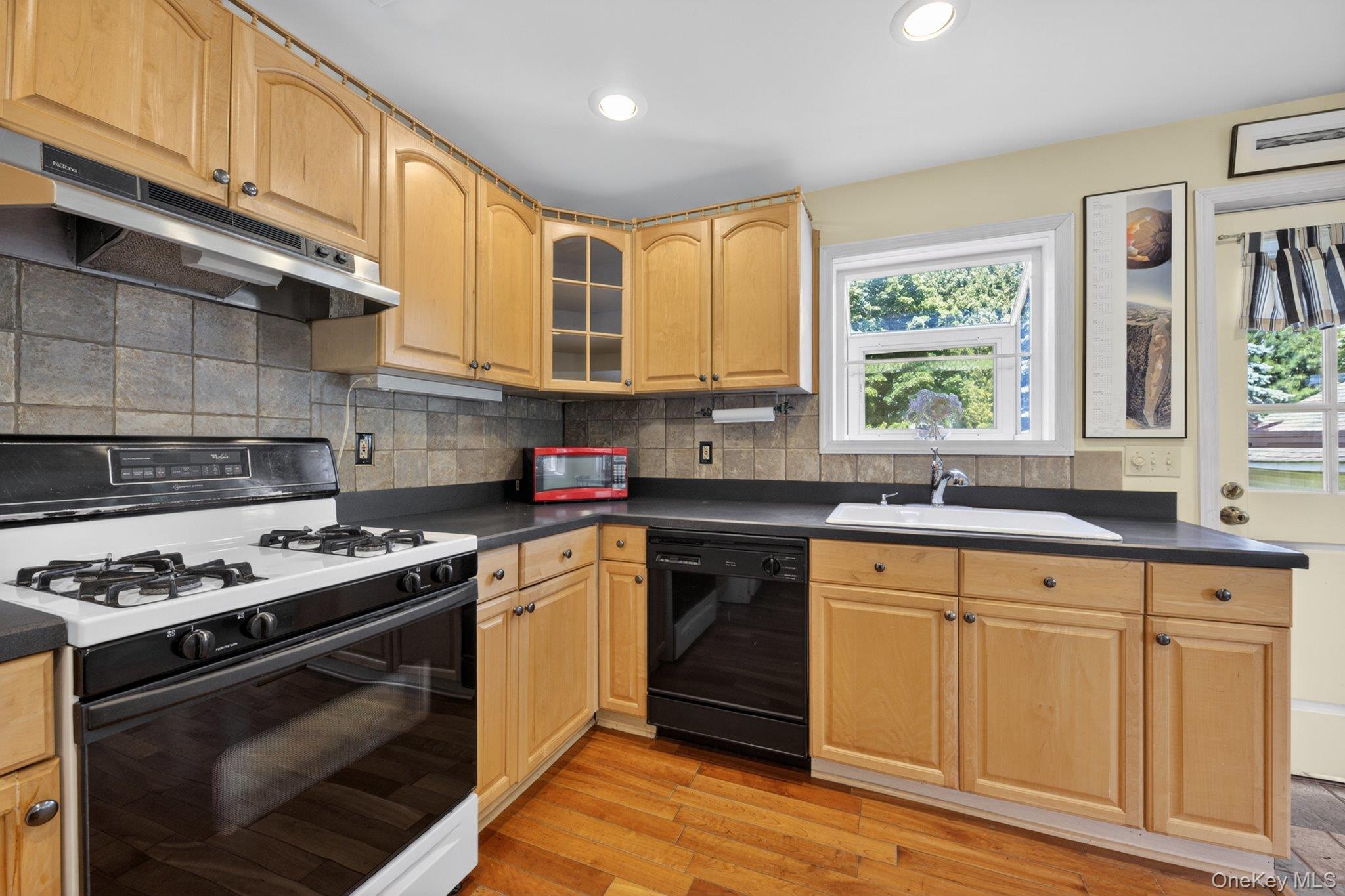 250 Rombout Avenue Beacon, NY 12508 - Photo 11 of 33 a kitchen with stainless steel appliances granite countertop a stove a sink dishwasher and white cabinets with wooden floor