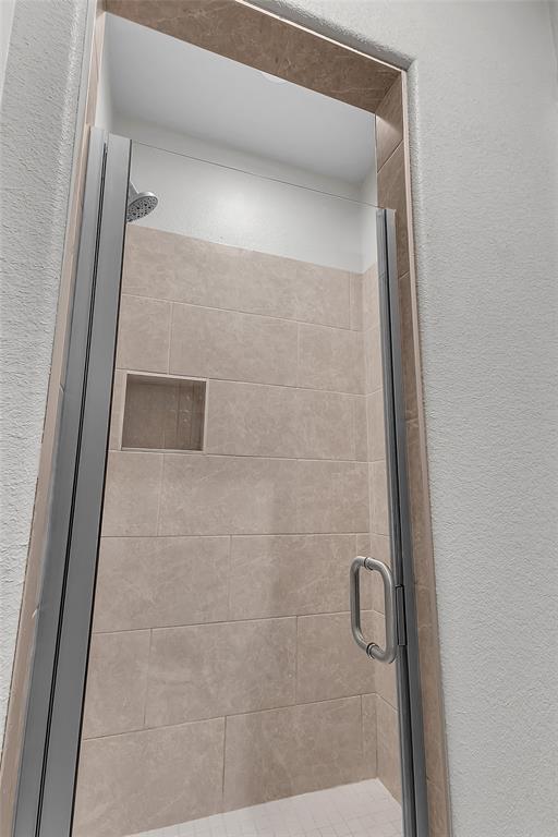 1014 Rennard Street Caddo Mills, TX 75135 - Photo 25 of 39 Shower enclosure featuring clear glass panels, a brushed metal handle, and neutral-toned rectangular wall tiles