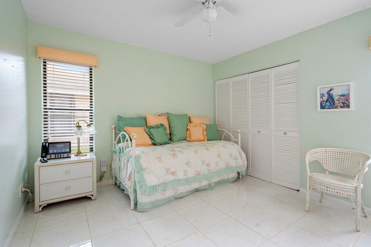 8299 Springlake Drive, Unit B Boca Raton, FL 33496 - Photo 19 of 31 a spacious bedroom with a bed and a chair