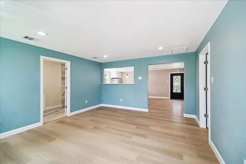 a view of an empty room with a window and wooden floor