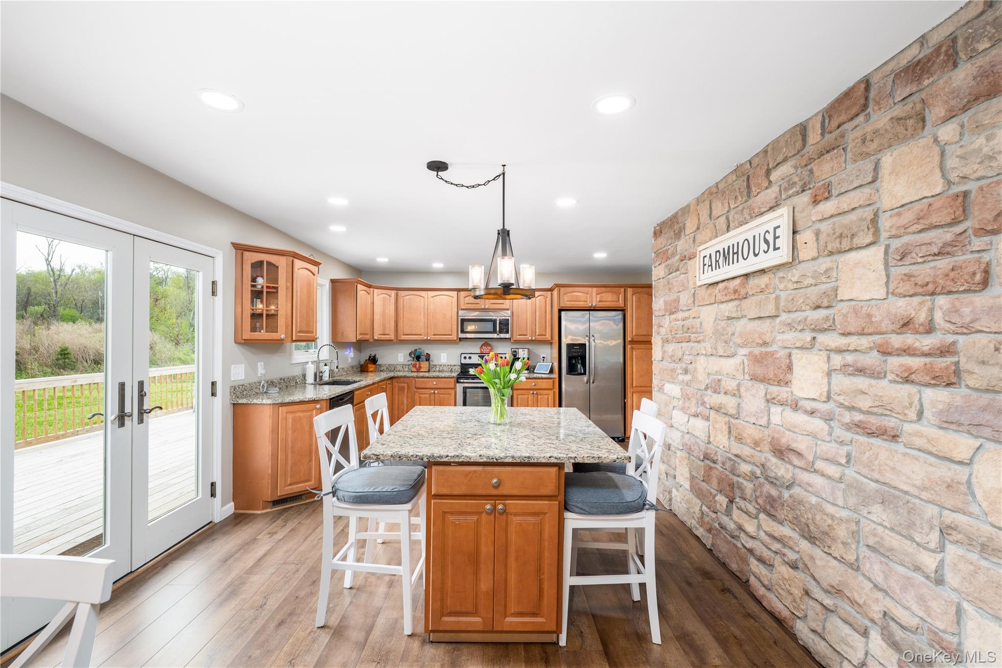 41 Diddell Road Wappingers Falls, NY 12590 - Photo 12 of 44 Open-concept kitchen featuring a stone accent wall, wood flooring, wood cabinetry, granite countertops, and French doors opening to a large single level deck