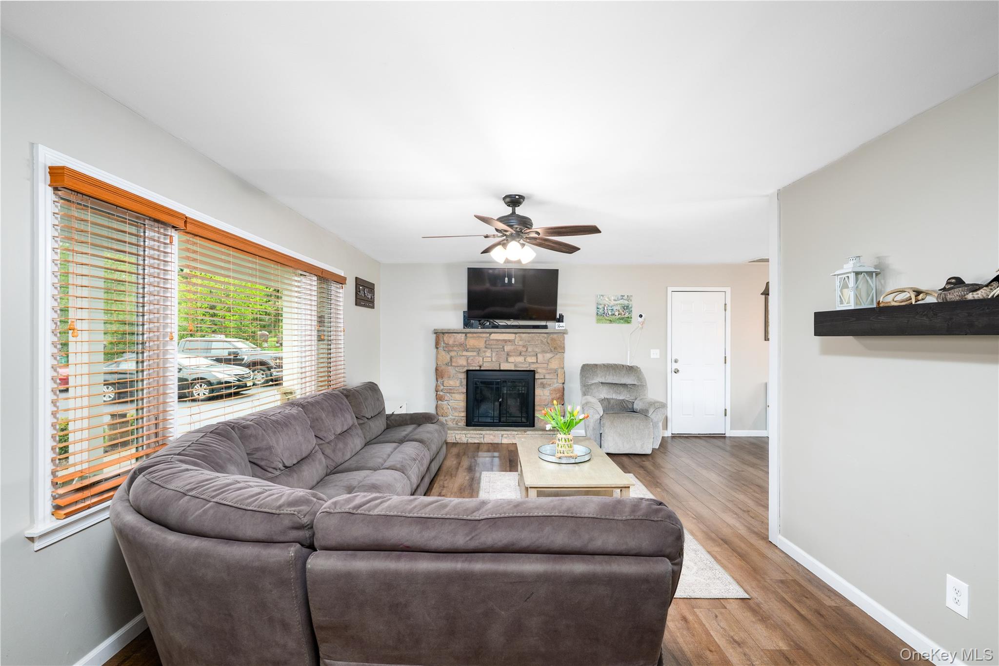 41 Diddell Road Wappingers Falls, NY 12590 - Photo 14 of 44 Spacious living area featuring wood flooring, a stone-faced wood fireplace with a hearth, and a ceiling fan