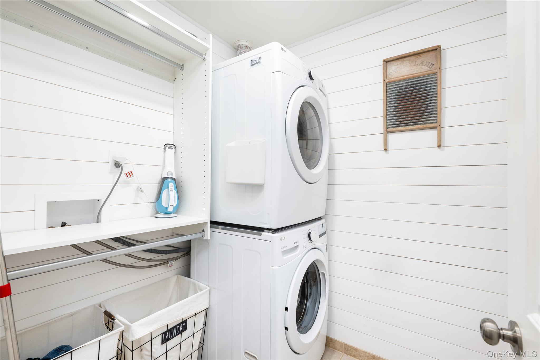 41 Diddell Road Wappingers Falls, NY 12590 - Photo 16 of 44 Main floor Laundry room featuring white shiplap walls, stacked washer and dryer, and a built-in shelving unit with hanging rods