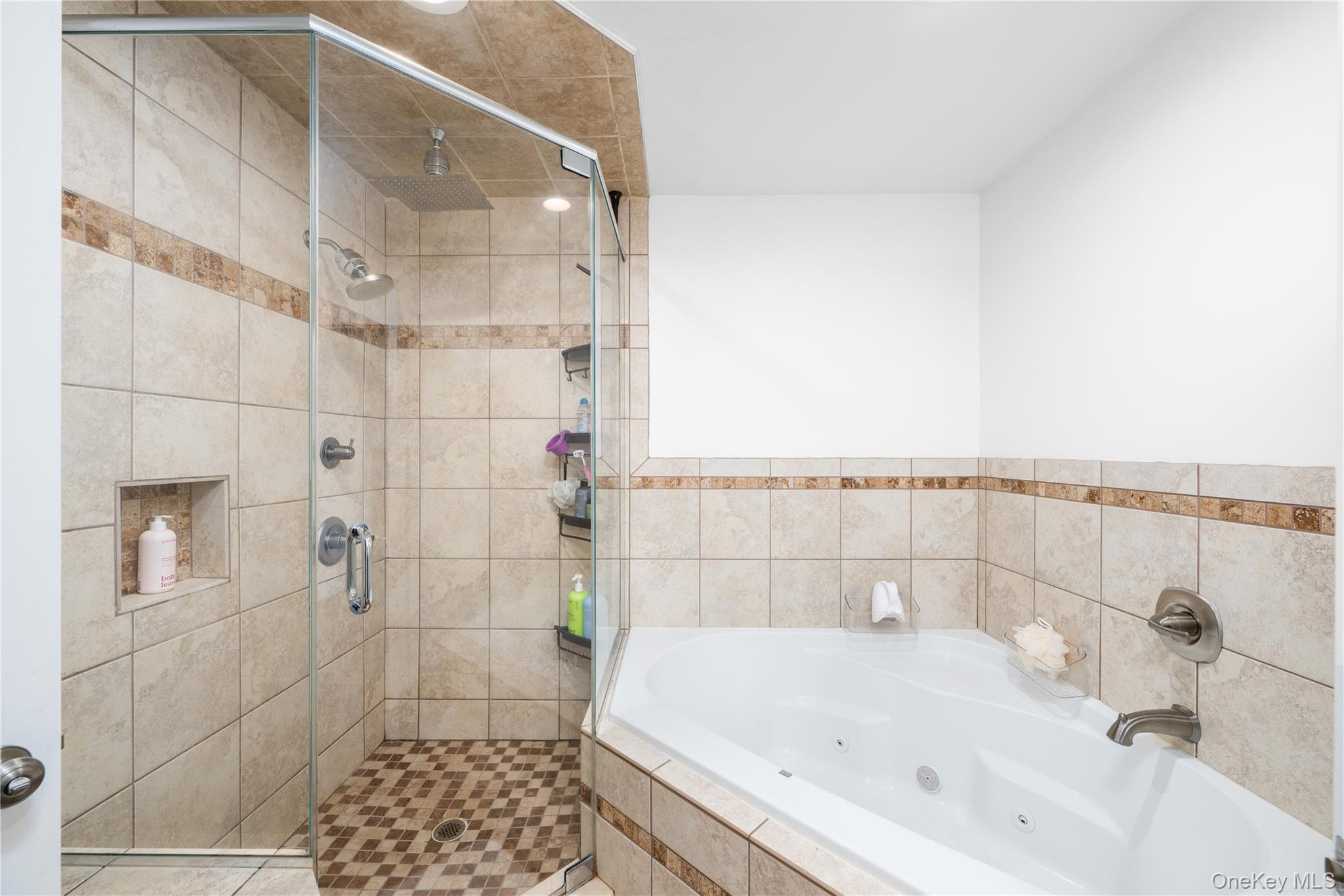 41 Diddell Road Wappingers Falls, NY 12590 - Photo 24 of 44 Ensuite bathroom featuring a corner jetted soaking tub, glass-enclosed shower, tiled walls, and a recessed shower niche