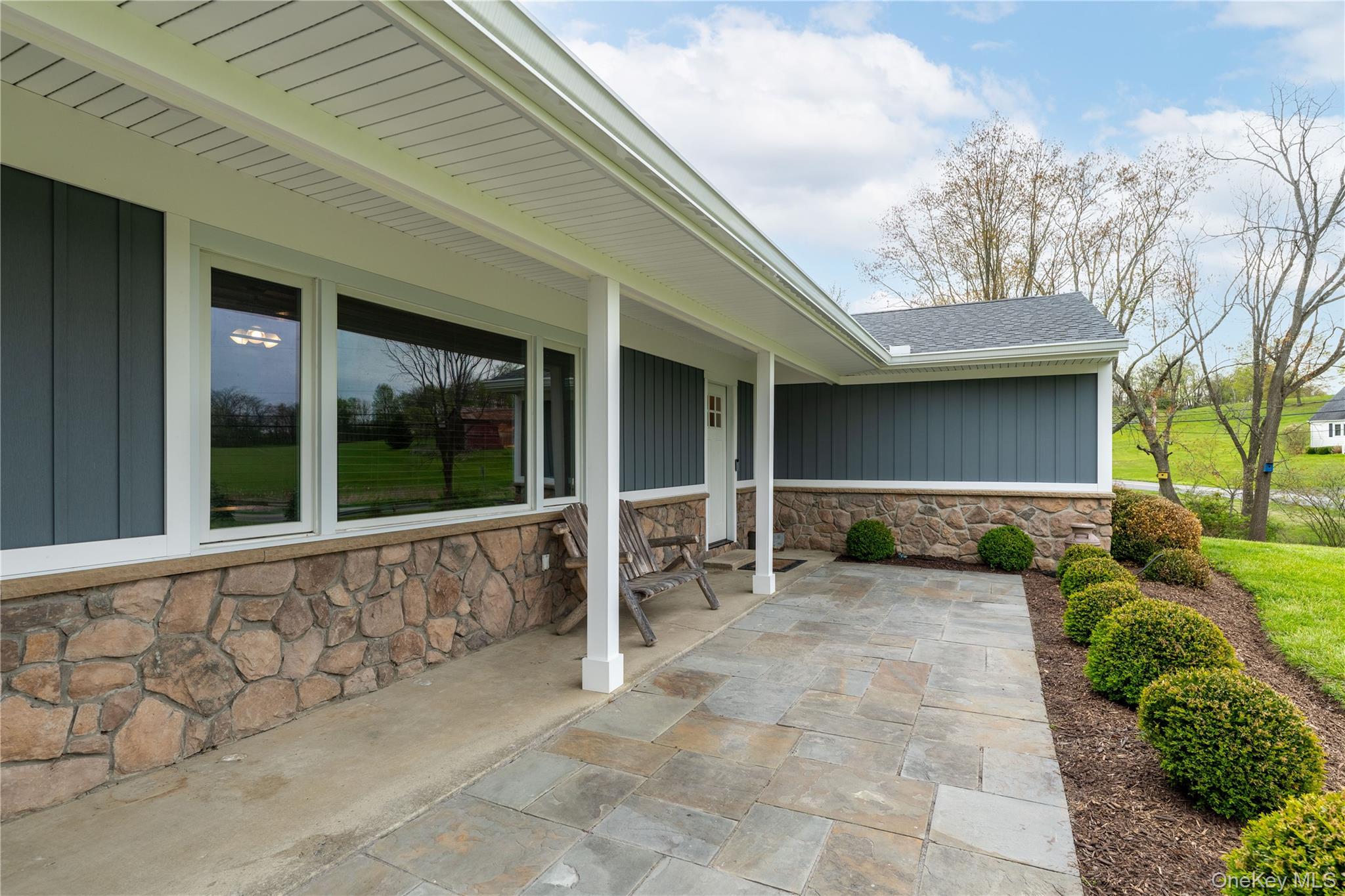 41 Diddell Road Wappingers Falls, NY 12590 - Photo 3 of 44 Stone and siding exterior featuring a covered patio with flagstone pavers, white columns, and a landscaped planting bed