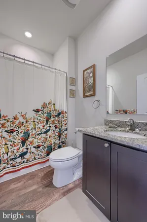 a bathroom with a granite countertop sink a toilet and a shower