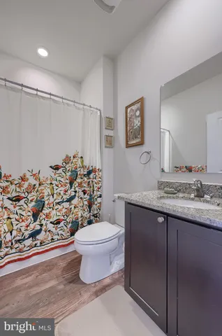 a bathroom with a granite countertop sink a toilet and a shower