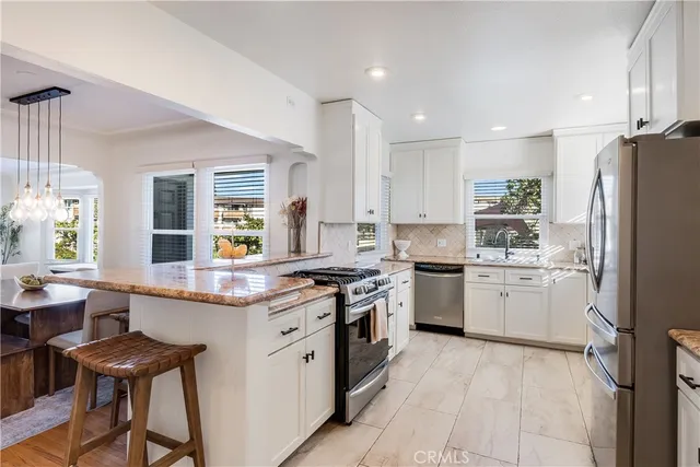a kitchen with a sink stove a refrigerator and white cabinets