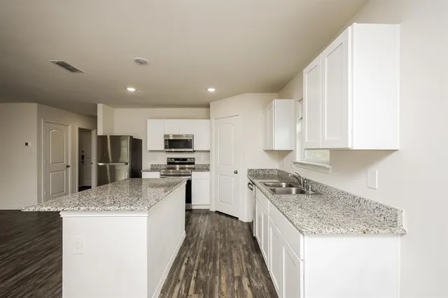 a kitchen with stainless steel appliances granite countertop a stove top oven a refrigerator a sink and dishwasher