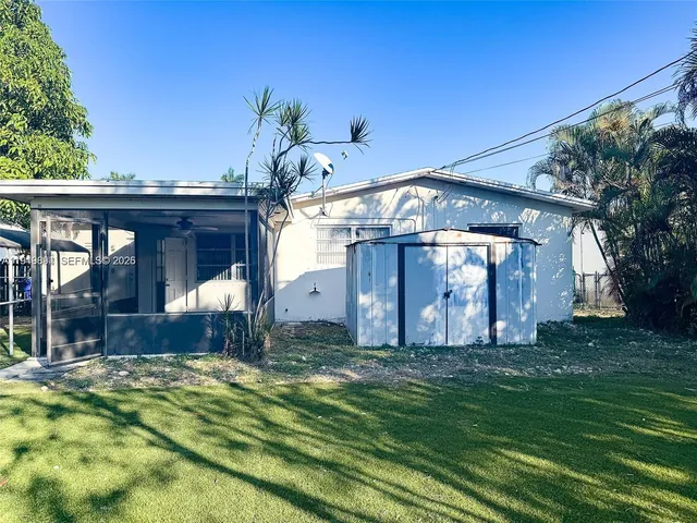 a view of a house with a small yard and a large tree