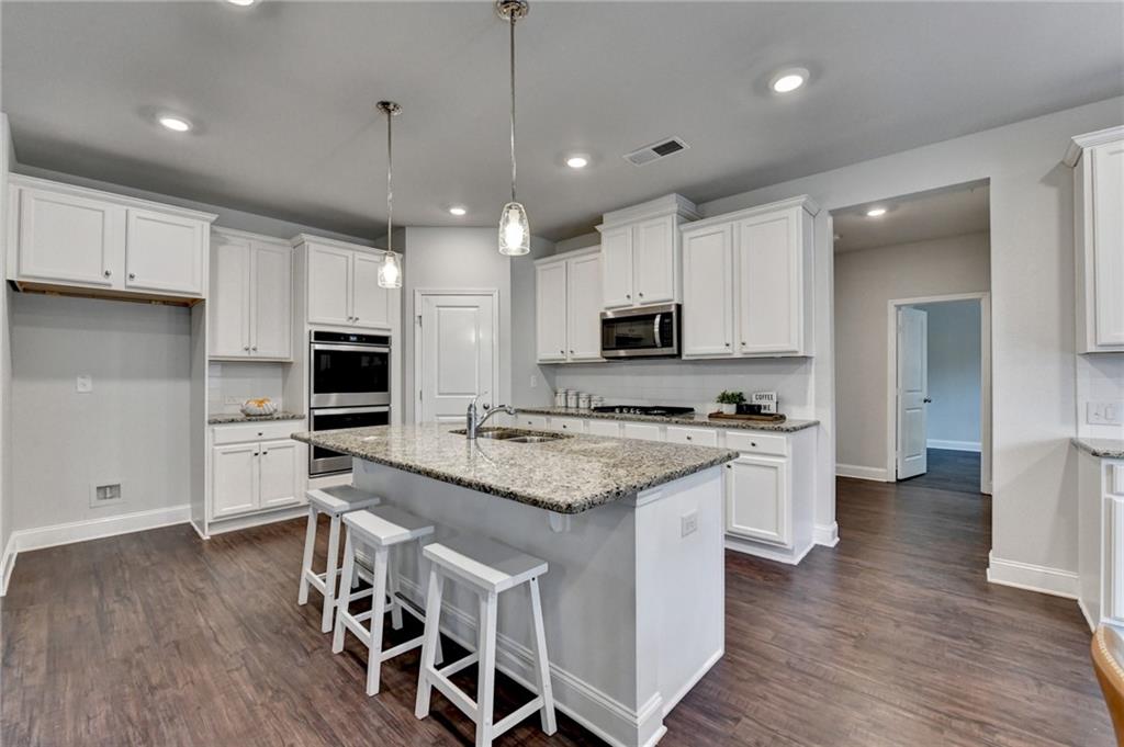 2017 Yvette Way Braselton, GA 30517 - Photo 15 of 75 a kitchen with stainless steel appliances granite countertop a stove top oven a refrigerator a sink and white cabinets with wooden floor