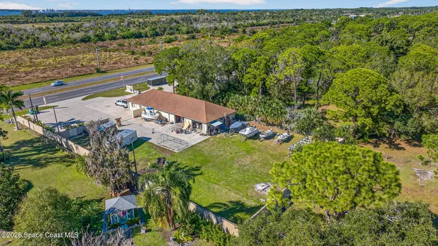 an aerial view of a residential houses with outdoor space and trees all around