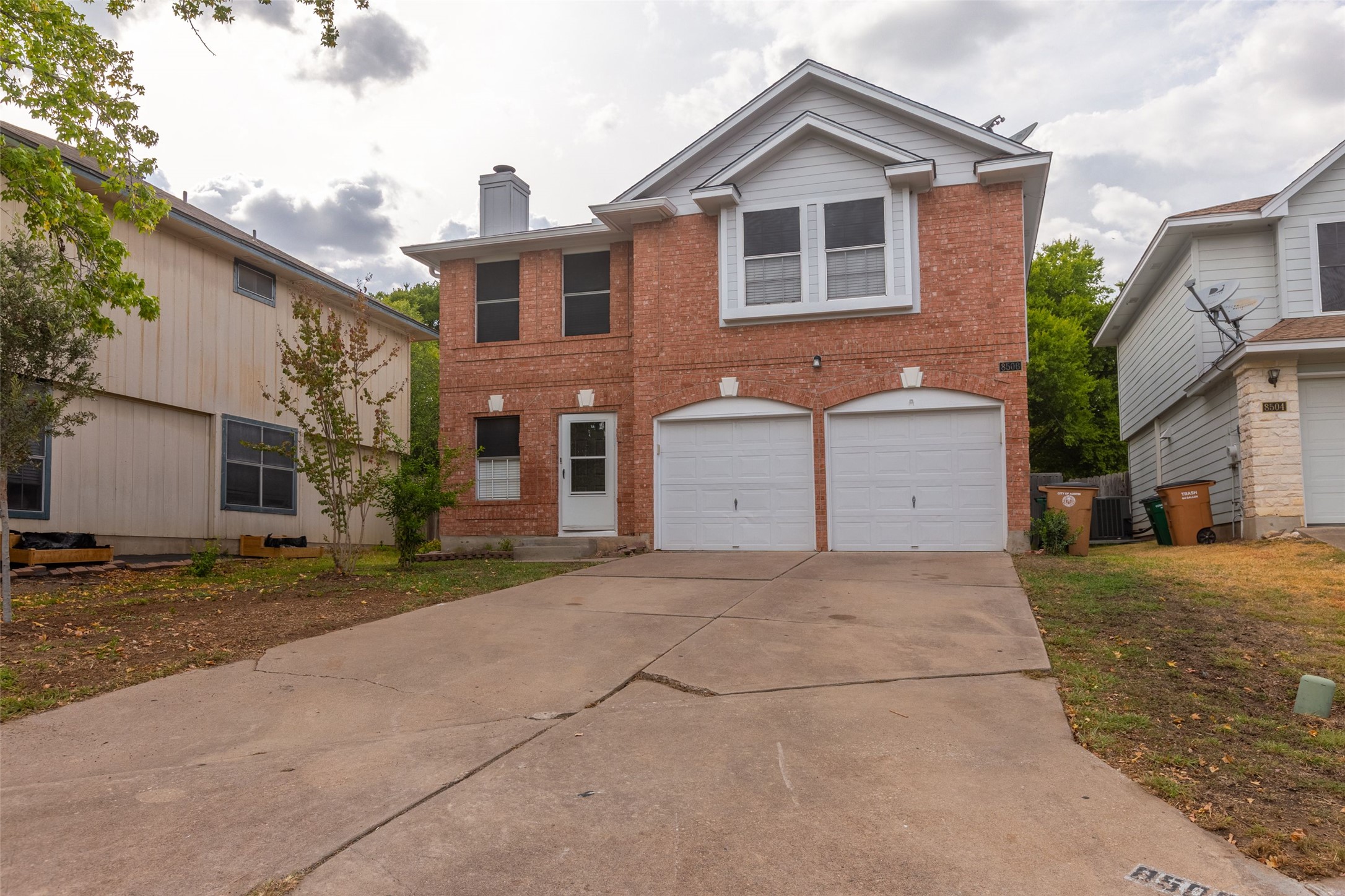 8506 Bisbee Court Austin, TX 78745 - Photo 20 of 20 Brick facade with white trim, featuring a two-car garage, a front entry door, and multiple windows