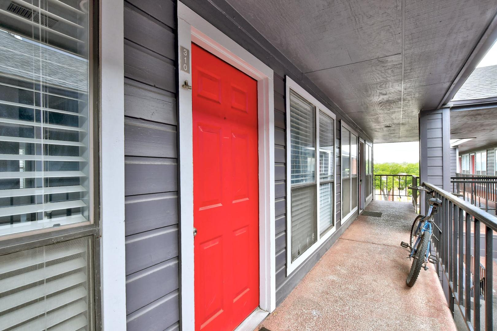 2804 Rio Grande Street, Unit 310 Austin, TX 78705 - Photo 3 of 22 Bold entry door welcomes to a well-lit corridor with a balcony view.