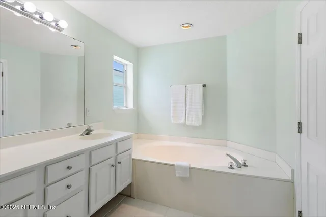 a bathroom with a tub a sink and mirror