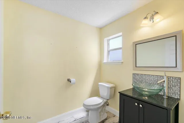 a bathroom with a granite countertop sink and a toilet