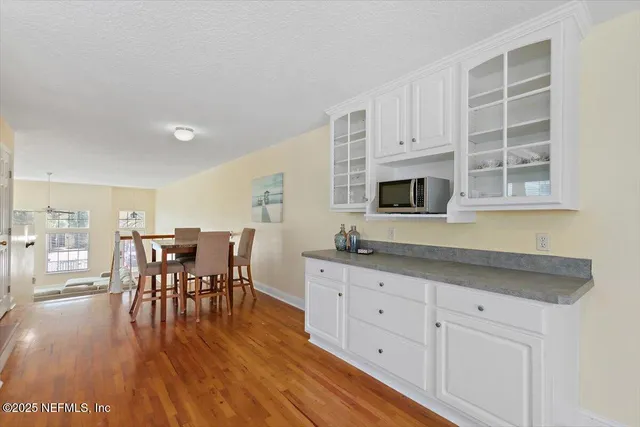 a kitchen with stainless steel appliances granite countertop a stove a sink a dining table and chairs with wooden floor
