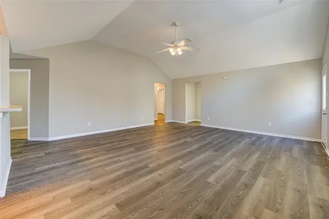 a view of empty room with wooden floor and ceiling fan