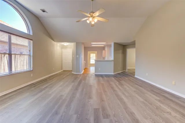 a view of empty room with wooden floor and fan