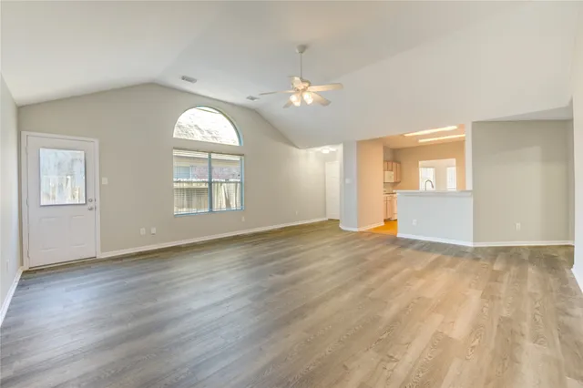 a view of empty room with wooden floor and fan