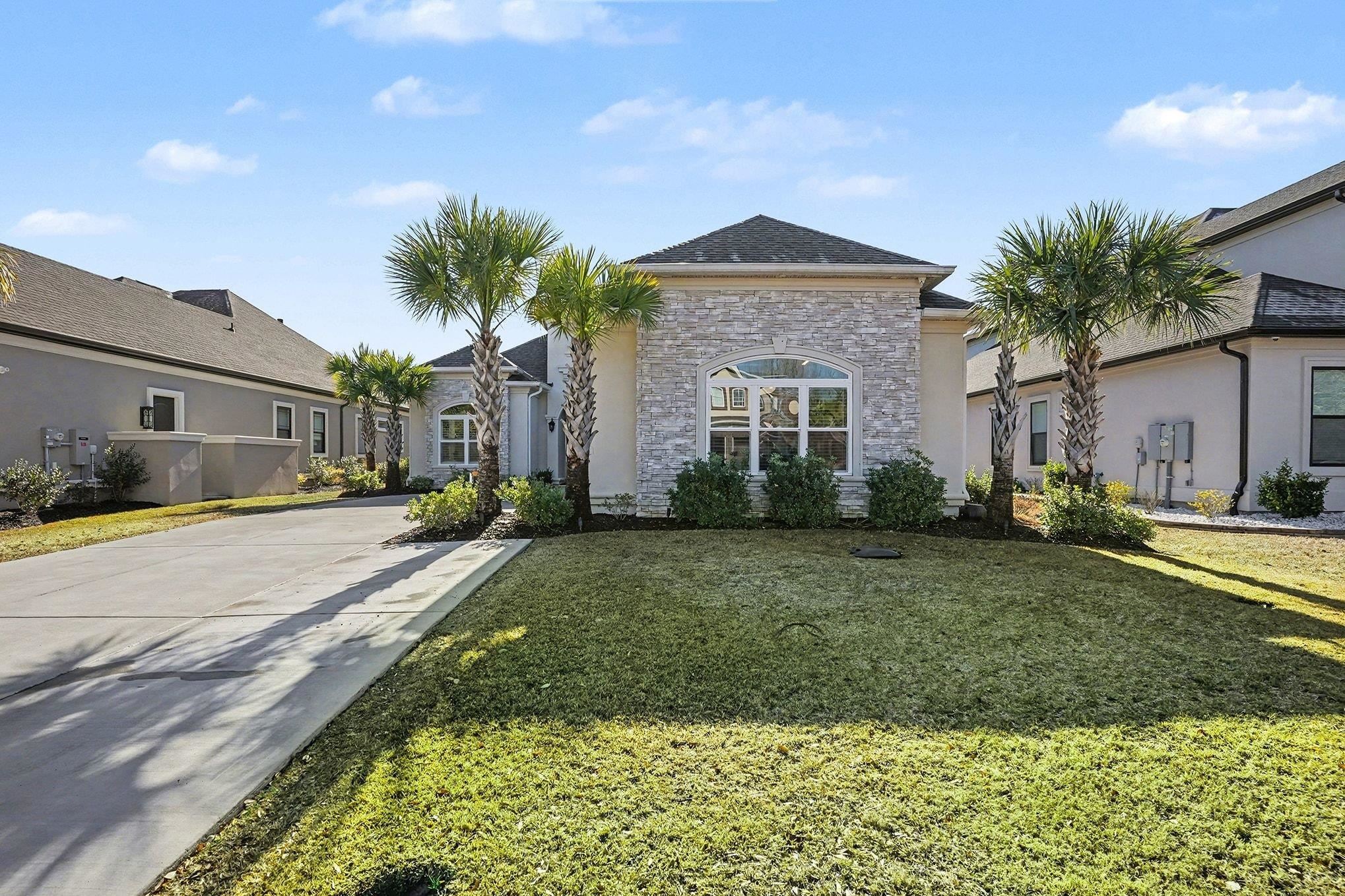 902 Shipmaster Avenue Myrtle Beach, SC 29579 - Photo 2 of 40 View of front facade with stone siding, a front yard, driveway, and stucco siding