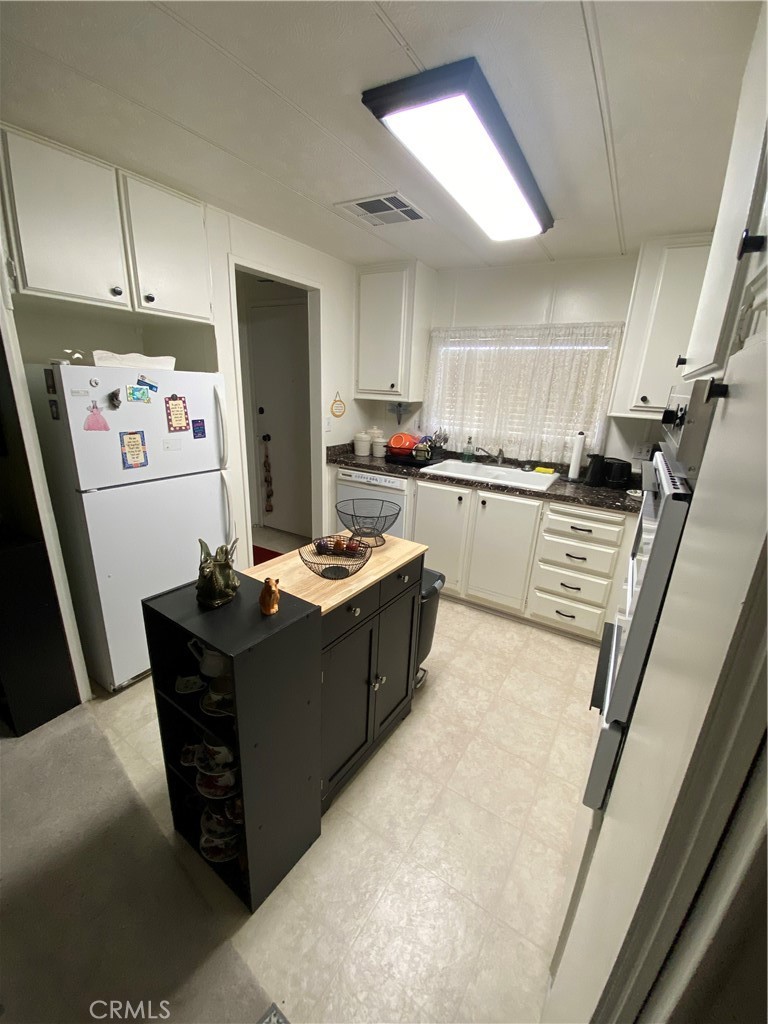 12680 4th Street, Unit 39 Yucaipa, CA 92399 - Photo 17 of 45 a kitchen with kitchen island cabinets a sink a window and stainless steel appliances