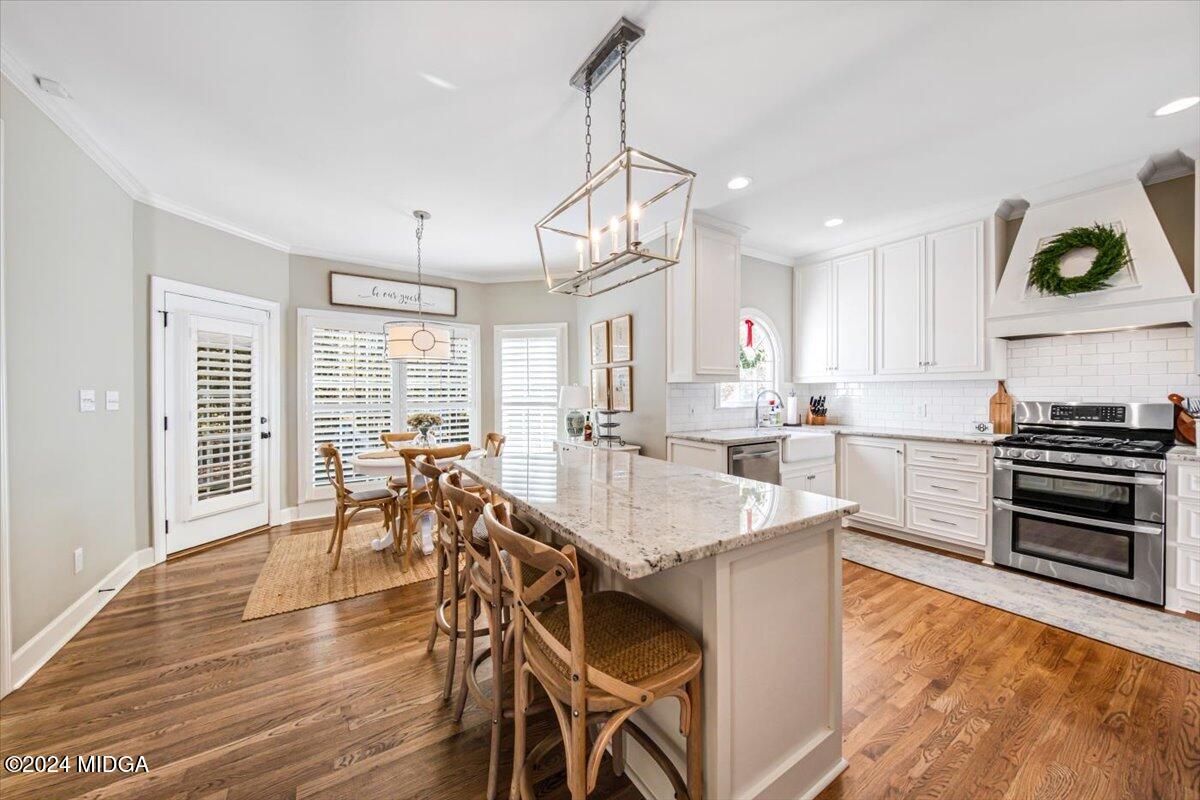 7701 Whittle Road Macon, GA 31220 - Photo 9 of 56 a kitchen with stainless steel appliances granite countertop a stove top oven a sink a dining table and chairs with wooden floor