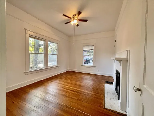 an empty room with wooden floor chandelier fan and windows