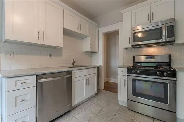 a kitchen with stainless steel appliances white cabinets and a stove top oven
