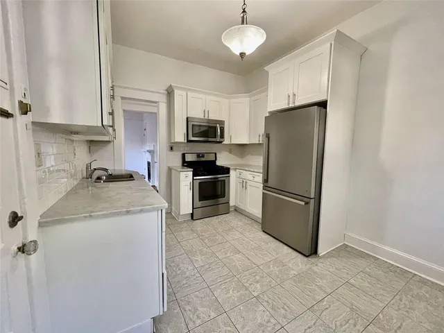 a kitchen with kitchen island a refrigerator sink and cabinets