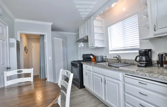 a kitchen with stainless steel appliances granite countertop a sink a stove a dining table and chairs