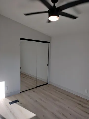 an empty room with wooden floor fan and windows