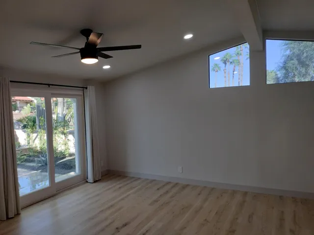 an empty room with wooden floor and windows