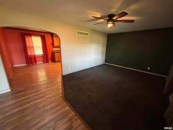 a view of an empty room with window and a ceiling fan