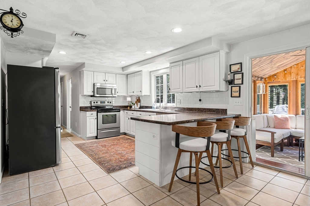 19 Powhatan Road Pepperell, MA 01463 - Photo 8 of 38 a kitchen with stainless steel appliances granite countertop a stove a refrigerator a sink a dining table and chairs