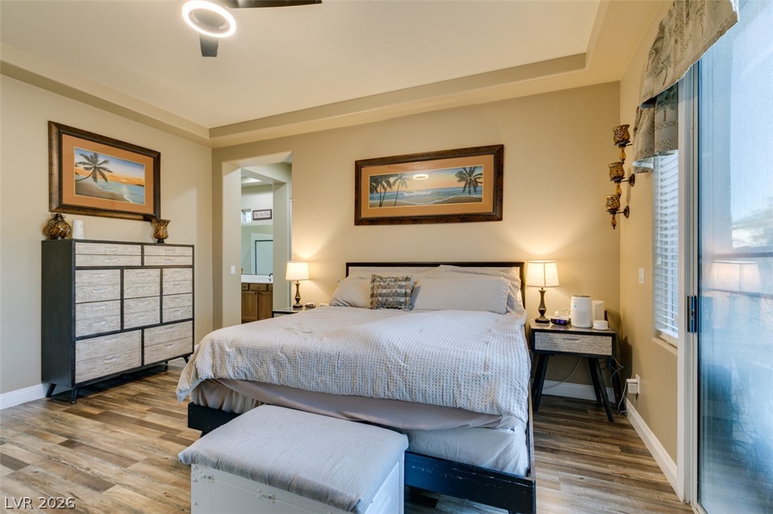 7524 Midnight Rambler Street Las Vegas, NV 89149 - Photo 37 of 51 Natural light illuminates this bedroom, offering wood-look flooring and easy access to an ensuite bathroom.