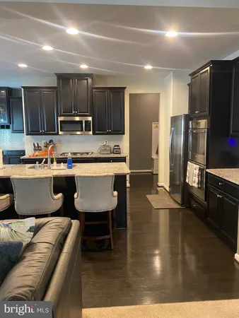 a kitchen with stainless steel appliances kitchen island granite countertop a sink a stove a refrigerator cabinets and chairs