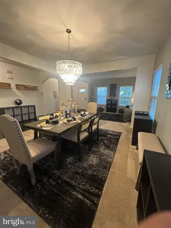 a dining room with wooden floor a chandelier a glass table and chairs