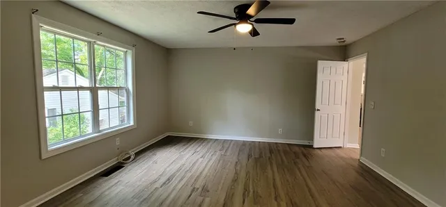 a view of empty room with wooden floor and fan