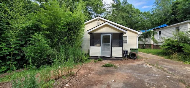 a view of a small house with a big yard and large trees