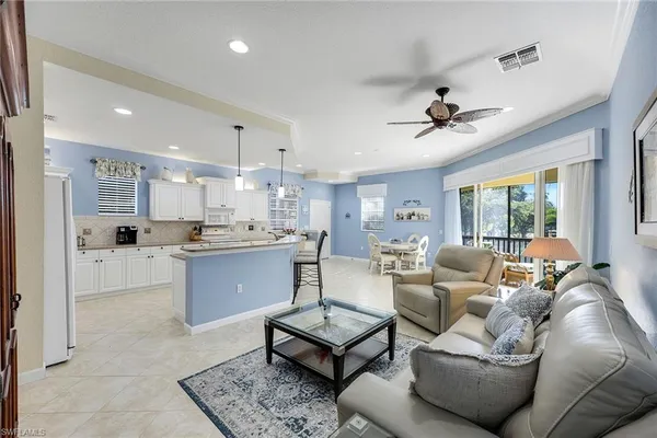 a living room with furniture kitchen view and a large window