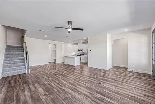 a view of empty room with wooden floor and ceiling fan
