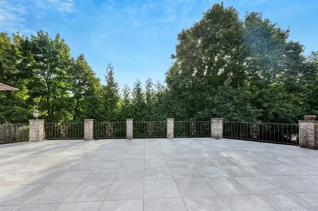 a view of a white house with a big yard plants and large trees